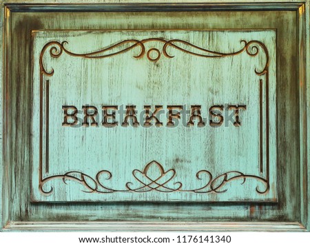 An old turquoise wooden signboard with an inscription breakfast.