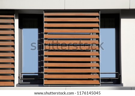 Light brown louvers / blinds over window. Lath structure. Abstract modern architecture background photo. Office or residential building exterior or interior fragment. Royalty-Free Stock Photo #1176145045