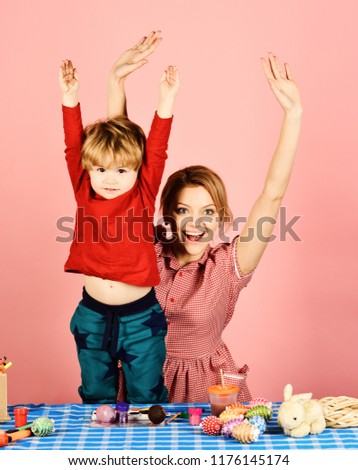 Mom and boy spend time together. Woman and child with happy faces put hands up on pink background. Easter celebration and parenthood concept. Mother and son making Easter decorations.