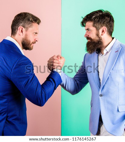 Business partners competitors office colleagues tense faces ready to compete in arm wrestling. Hostile or argumentative situation between opposing colleagues. Business competition and confrontation.