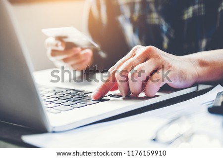 Man's hands typing laptop keyboard and holding credit card online shopping concept Royalty-Free Stock Photo #1176159910