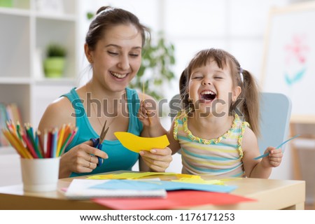 mother with child daughter in a yellow dress fun cut scissors colored paper Royalty-Free Stock Photo #1176171253
