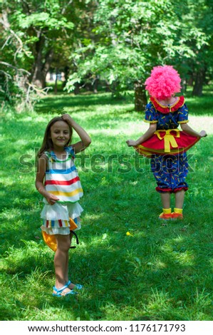 clown plays with a girl in park, catch-up