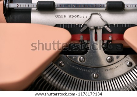 Nice retro typewriter with a paper sheet with a printed phrase "Once upon..." in the studio. Closeup horizontal photo.