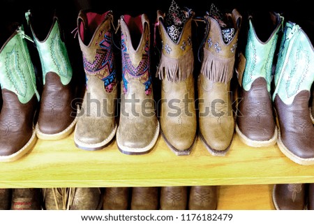 Colorful cowboy boots on shelf for fashion shoes Royalty-Free Stock Photo #1176182479