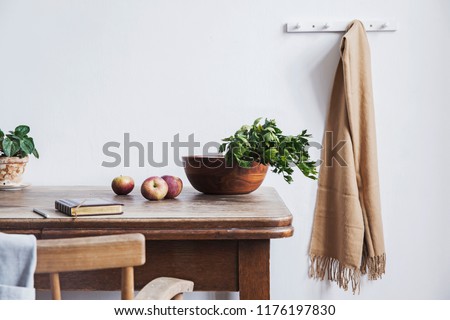 Vintage interior design of kitchen space with small table against white wall with simple chairs and vegetables. Minimalistic concept of kitchen space.