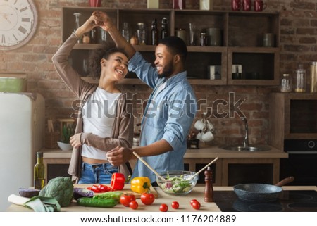 Happy romantic couple dancing in kitchen while cooking together Royalty-Free Stock Photo #1176204889