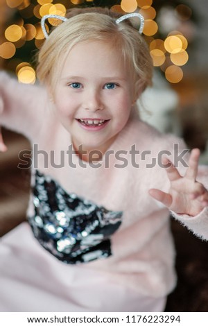 The beautiful smiling girl with a fair hair indoors with a Christmas interior