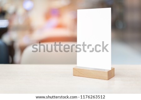 Mock up Label the blank menu frame in Bar restaurant ,Stand for booklets with white sheet on wooden table cafeteria blurred background