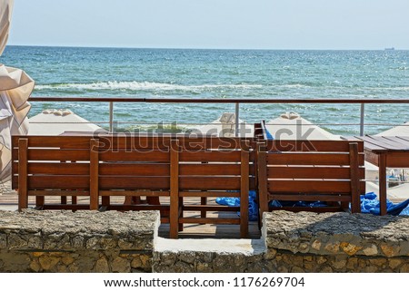 brown wooden bench against the blue sky and sea waves