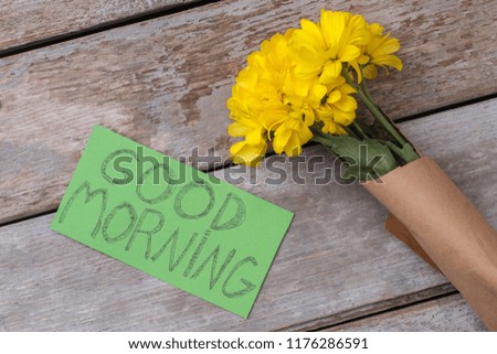 Yellow jerusalem artichoke flowers and good morning note. Top view. Old rustic wooden background.