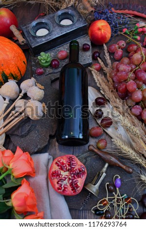 Autumn-season still life with grapes, wheat, poppy, roses, pips and wine bottles