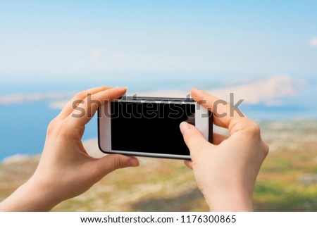 Female hands taking a photo of the landscape. Cropped shot view of woman's hands holding smart phone with blank copy space screen for your photo.