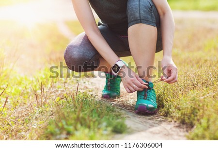 Active woman tying running shoes outdoor. Healthy lifestyle concept
