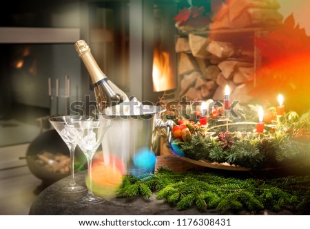 Home decoration. Bottle of champagne and fireplace. Christmas and new year. Candlelight dinner. Retro style toned picture