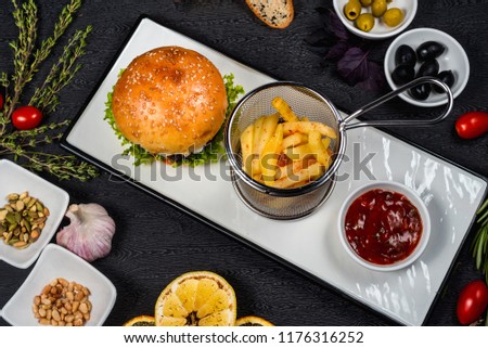 delicious hamburger with French fries and tomato sauce on a white plate