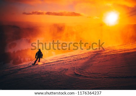 Man ski in ski resort. Winter sport photo. Orange sunset light in background. Edit space. Christmas and New Year time, snowy photo, edit space
