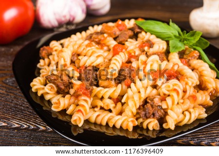 Pasta (spirals pasta)  Bolognese. Tagliatelle with minced meat  on a black plate on a dark wooden background.. Royalty-Free Stock Photo #1176396409