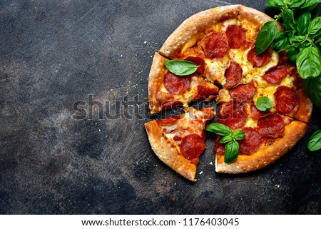 Traditional italian pizza pepperoni with salami and cheese on a dark slate, stone, metal or concrete background.Top view with copy space.