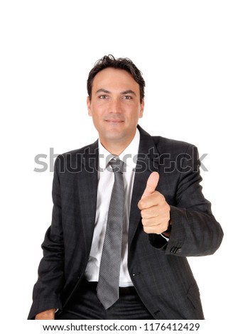 A young business man sitting in a dark gray suit and tie showing his
approval with his thump up, isolated for white background
