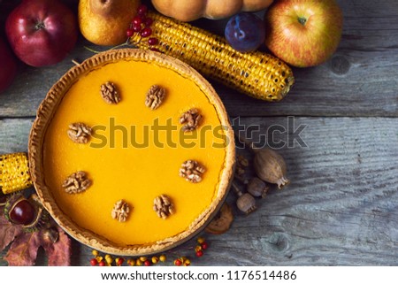 Fresh and tasty homemade pumpkin pie with autumn decoration over wooden backgound