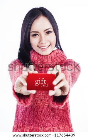 Portrait of excited woman wearing red sweater and showing a red gift card. isolated on white