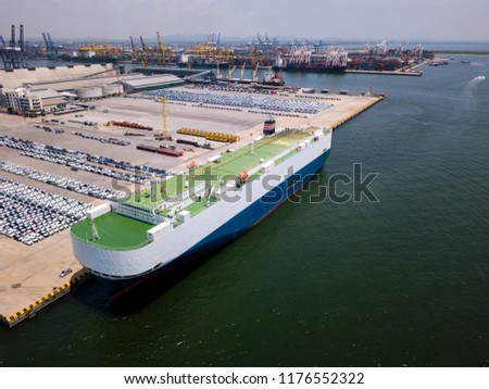 Aerial view of logistics concept floating dry dock servicing cargo ship and commercial vehicles, cars and pickup trucks waiting to be load on to a roll-on/roll-off car carrier ship at Laem Chabang Royalty-Free Stock Photo #1176552322