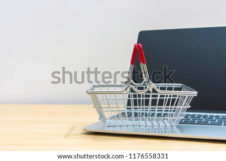 Mini shopping basket with laptop keyboard on wood table background.
Shopping online concept.
selective focus.