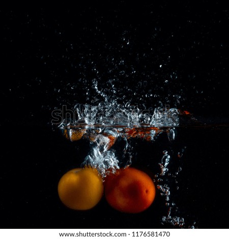 two tomatoes beautifully drowning leaving a spectacular splash of water over themselves concept of eating
