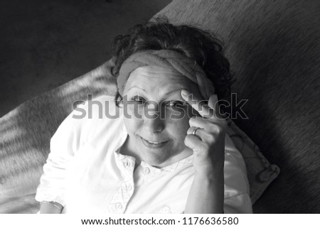 This is a black and white photo. The woman is laughing and thinking. The woman has a braided band.
