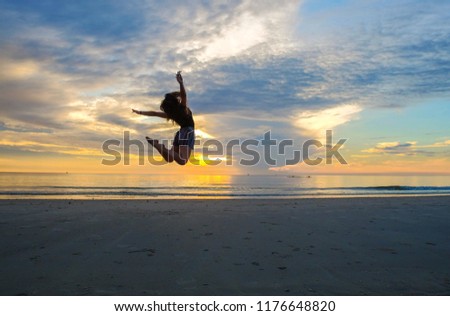 A summer concept picture of jumping woman in action on beach in the evening sunset.