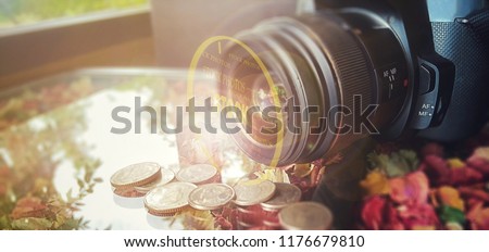 make money with stock photos concept, camera lie on the colorful table with coins in front of the camera lens, add an effect of circle line and "stock photos" text on it