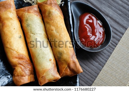deep fried spring rolls.Place near the ketchup.Thai food.In a black plate on the table.At the cafe