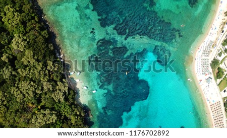 Aerial bird's eye view photo taken by drone of tropical seascape and sandy beach visited by small boats with turquoise clear waters and pine trees