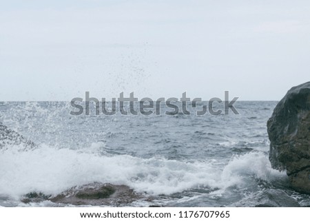 Waves are beating against rocks on the seashore, the ocean in cloudy weather.
