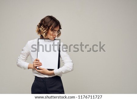 A woman holds a folder with documents in her hand and looks away                          