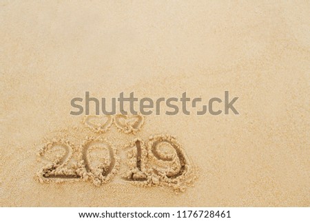 Written of two hearts above year of 2019 on sand of beach with copy space. Happy new year 2019 concept Royalty-Free Stock Photo #1176728461