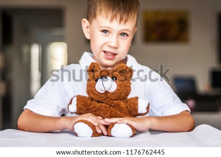 Funny and naughty Caucasian child with a toy teddy bear. Happy childhood concept.