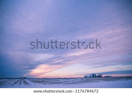 Winter Sunset over Snowy American Corn Fields in Winter with Cloudy Sky Royalty-Free Stock Photo #1176784672