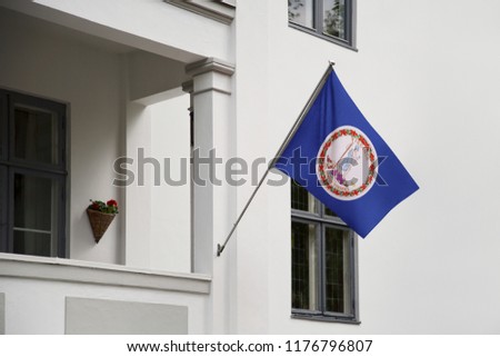 Virginia flag. Virginia state flag hanging on a pole in front of the house. State flag waving on a home displaying on a pole on a front door of a building. Flag raised at a full staff.
