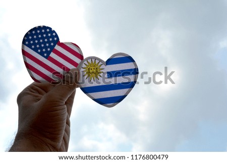 Hand holds a heart Shape USA and Uruguay flag, love between two countries