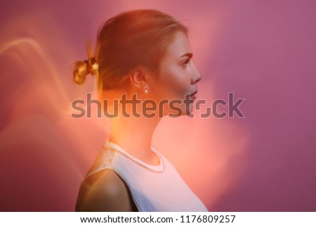 Black and white image on long exposure. Beauty portrait young blonde girl on pink wall isolated.