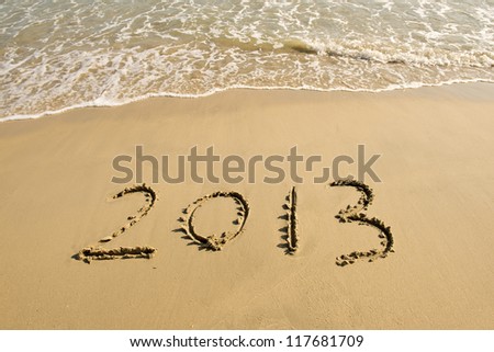 Year 2013 hand written on the white sand in front of the sea Royalty-Free Stock Photo #117681709