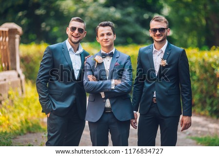 Groomsmen and groom posing outdoors on the wedding day. Funny wedding moment for best groom friends. Mens hug each other. Royalty-Free Stock Photo #1176834727