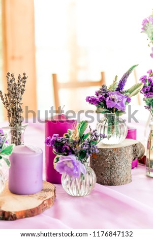 Purple lavender wedding. Table decor with dry lavender, green and white flowers. Candles, wooden rustic vases, Glass jars, lace bottles, sawed wood.