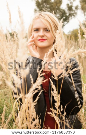 A romantic blonde walking in an amazing field. Red dress. Dried grass.