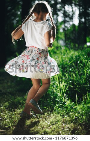 Little girl  spinning around in sunlight. Summer. 