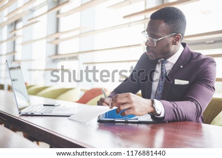 A young businessman signs a contract in a conference room.