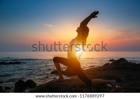 Silhouette fitness yoga women on the coast during an amazing sunset.