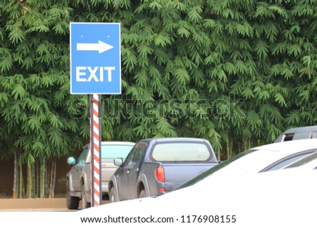 At the park there are many cars , exit sign to the road.